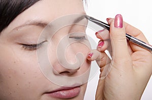 Makeup artist in the process of makeup brings eyebrow pencil model