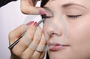 Makeup artist in the process of makeup colors eyelashes model