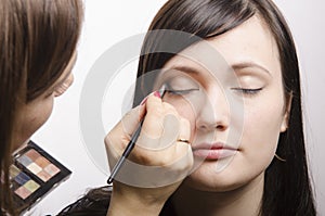 Makeup artist in the process of makeup colors upper eyelids model