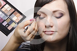 Makeup artist in the process of makeup colors upper eyelids model