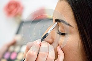 Makeup artist putting make-up on an woman`s eyebrows