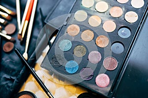 Makeup artist set. Close-up of a palette of eyeshadows of different colors and brushes for applying makeup on a blurred