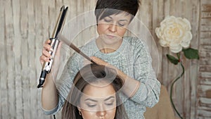 Makeup artist stylist works with model. hairdresser does the hair styling of the model. woman is working a styler with