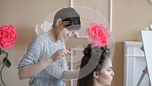 Makeup artist stylist works with model. hairdresser does the hair styling of the model. woman is working a styler with