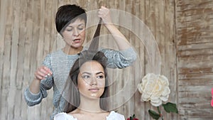 Makeup artist stylist works with model. hairdresser does the hair styling of the model. woman is working a styler with