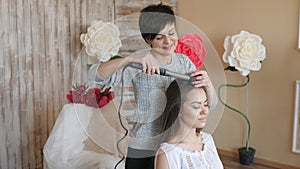 Makeup artist stylist works with model. hairdresser does the hair styling of the model. woman is working a styler with