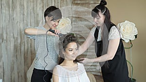 Makeup artist stylist works with model. hairdresser does the hair styling of the model. woman is working a styler with