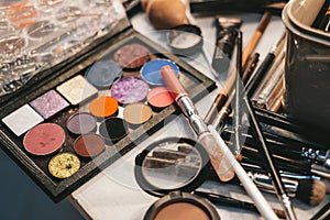 Makeup artist tools. the work table of the make-up artist. eyeshadow, blush, brushes and foundation close-up top view. cosmetics