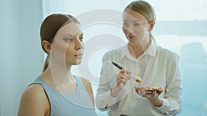 Makeup artist work in her beauty studio. Portrait of Woman applying by professional make up master.