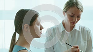 Makeup artist work in her beauty studio. Portrait of Woman applying by professional make up master.