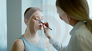 Makeup artist work in her beauty studio. Portrait of woman applying by professional make up master.