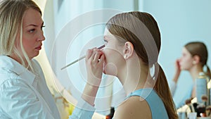 Makeup artist work in her beauty studio. Portrait of woman applying by professional make up master.