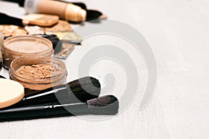 Makeup background. Make-up powder, foundation, concealer with brushes and cosmetic sponges on concrete surface with copy space