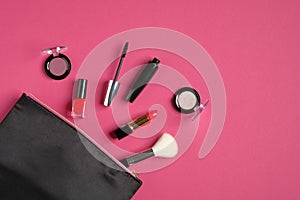 Makeup bag organizer with cosmetic products and professional make-up artist tools on pink background. Flat lay, top view. Beauty