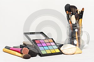 Makeup and beauty concept. Colorful cosmetic on plate with brushes on table