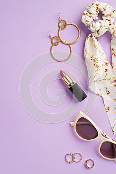 Makeup beauty concept. Top view vertical photo of stylish scarf scrunchy lipstick sunglasses gold earrings and rings on isolated