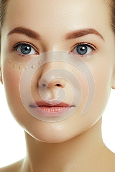 Daily makeup. Beauty concept. Young woman with drops of cream on her beautiful face on white background