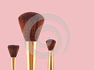 Makeup brush for applying face powder isolated on pink background.
