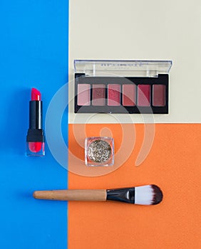 Makeup brush and cosmetics on colorful backgrounds