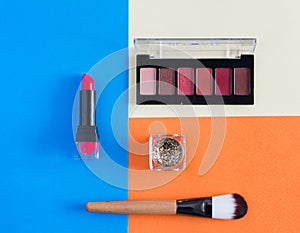 Makeup brush and cosmetics on colorful backgrounds