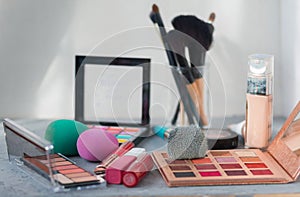 Makeup brush and cosmetics on grey table.