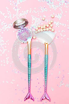 Makeup brush and eyeshadow on pink glitter background. Vertical