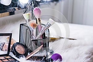 Makeup brush and glass on white fur backdrop, Beauty concept