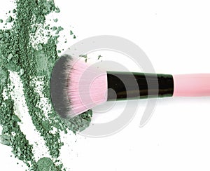 Makeup brush with green crushed eye shadow, isolated on white macro.