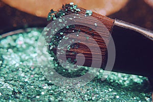Makeup brush on green shiny shadows. Bright shadows with glitter glitter.