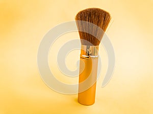 Makeup brush with loose cosmetic powder on white background