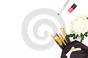 Makeup brush in the makeup, red lipstick, pink nail Polish and a chrysanthemum flower on a white background. Minimal feminine conc