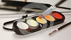 Makeup brush moving over multicolor eye shadows palette