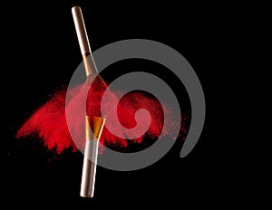 Makeup brush with red powder explosion on black background