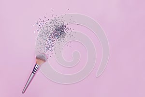 Makeup brush and strar shapped small confetti on pastel pink background.