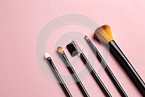 Makeup brush and white business card on pink background. A horizontal template for a makeup artist's business card