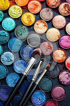 Makeup brushes and colorful eyeshadows on black background. Generative AI