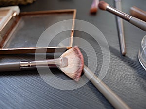 Makeup brushes and cosmetics on black wooden table. Top view