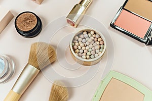 makeup brushes and powder, lipsticks, shadows on beige background. make up mockup