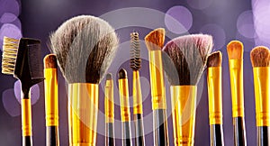 Makeup brushes set over black holiday blinking background. Various professional make up brush on dark backdrop in studio