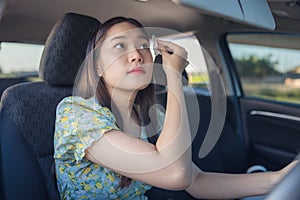 Makeup in the car, young woman applying makeup while driving