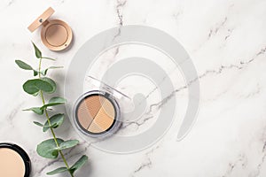 Makeup concept. Top view photo of contouring palette eyeshadow compact powder and eucalyptus on white marble background with