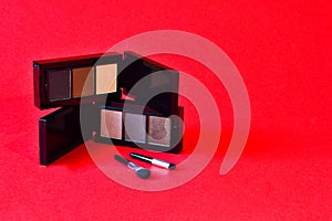 Makeup cosmetics kit. Eyeshadow on a red background. Decorative facial skin products. Beauty concept. Copy space.