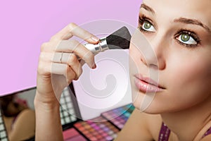 Makeup and cosmetics - woman using blush brush
