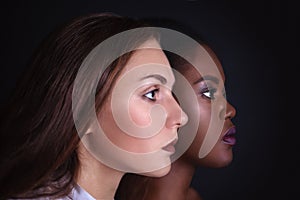 Makeup. Double female portrait. Caucasian and afro-american women posing in studio over black background