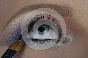 Makeup, eye shadow, blue shadows, make-up artist draws eyes, blue eye of a girl. Brush for cosmetics for eyes. Beautiful