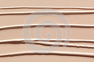 Makeup foundation creamy texture background. Skin tone concealer, color corrector strokes photo