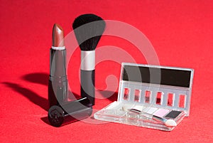 Makeup items on red background with high-contrast lighting