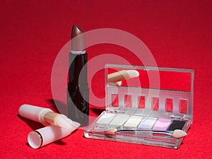 Makeup items on red background with high-contrast lighting