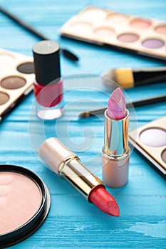 Makeup lipstick and cosmetics on blue background. Flat lay, top view. Beauty and fashion concept