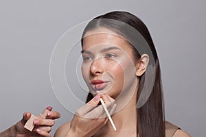 Makeup. Make-up artist applies pink lipstick to a lips of cute female model woman